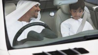 A driver makes sure his young passenger is properly strapped into his seat before setting off.