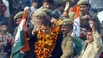 Congress party candidate Sham Lal Sharma, wearing garlands, waves to supporters after his victory in Jammu, India.