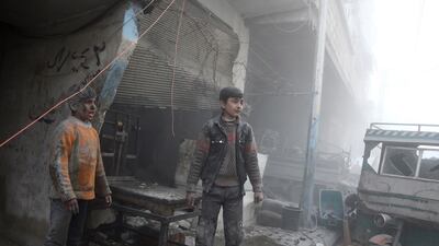 Children emerge from a shop after air strikes in the town of Saqba in the Eastern Ghouta region on February 8, 2018. Abdulmonam Eassa / AFP