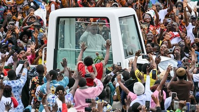 Pope Leo XIV waves from the 'Popemobile' to the gathered crowd as he arrives to lead Holy Mass at Bamenda Airport in Cameroon. AFP