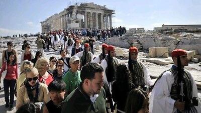 Tourists walk beside Greek presidental Evzoni guards as they descend from the Acropolis archaeological site in Athens. AFP