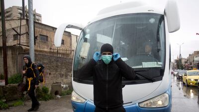A Palestinian policeman stops tourist busses as preventive measures are taken against the coronavirus. AP