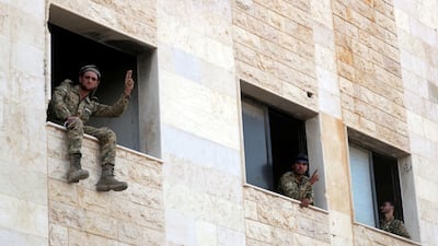 Turkey-backed Syrian rebel fighters gesture from a building in the town of Tal Abyad, Syria. Reuters
