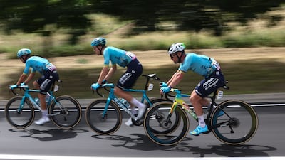 Astana Qazaqstan rider Mark Cavendish, right, cycles with teammates Michele Gazzoli, left, and Cees Bol as they attempt to catch the peloton. AFP