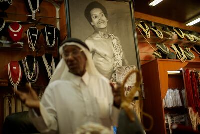 Beneath an old photograph taken when he was a young man, former pearl diver Saad Ismail chats to clients in his pearl shop. AP Photo