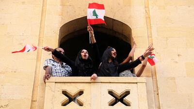 Women hold Lebanese flags as they stand on a balcony during a protest targeting the government over an economic crisis, in Beirut, Lebanon. Reuters