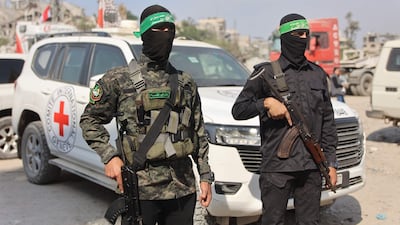 Hamas fighters stand guard as others search for the bodies of Israeli hostages alongside Red Cross workers in the east of Gaza on Sunday. AFP