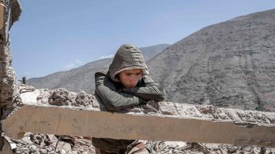 A young earthquake survivor leans on a cement beam amid the rubble of a destroyed building in a village near Amizmiz. AFP