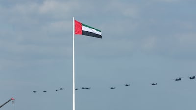 The UAE's national flag flies and a formation of military helicopters symbolises dedication and purpose over the Corniche in Abu Dhabi on Saturday