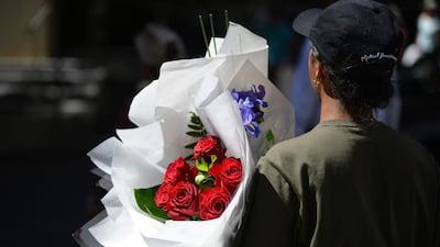A woman carries a bunch of roses in Sydney on February 13, 2017. Love may be in the air on February 14 but St. Valentine's Day is also peak time for scamming lonely hearts for money, an Australian government body warned on February 13. / AFP / Peter PARKS
