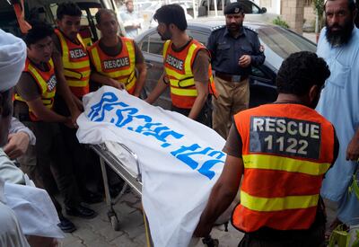 Rescue workers move the body of Ikramullah Gandapur, who was killed in the suicide bombing in Dera Ismail Khan on Sunday, July 22. AP Photo