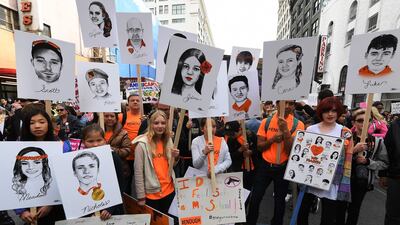 Students hold portraits of victims of Florida's Marjory Stoneman Douglas High School shootings as people protest for tighter gun laws during the March For Our Lives rally / AFP