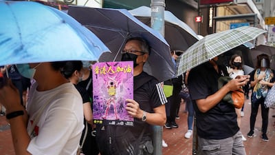 A man wears a mask holding a poster which reads "Go Hong Kong people". AP Photo