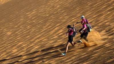 Women run down a sand dune as they take part in the desert trek, the Rose Trip Maroc. AFP