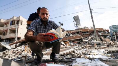 A Palestinian man holds a book he removed from under the rubbe of the Kuhail building which was destroyed in an early morning Israeli airstrike on Gaza City on May 18. AFP