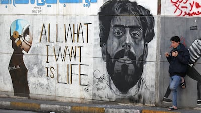 An Iraqi man leans on a wall bearing murals inspired by ongoing anti-government demonstrations in the capital Baghdad's Tahrir square on January 14, 2020. AFP