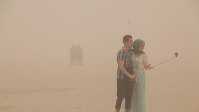 People take photos during stormy conditions in Umm Suqeim Beach. Mona Al Marzooqi / The National