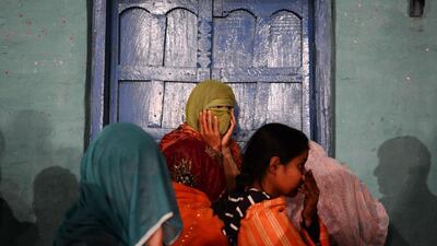 Indian revellers wait outside their home to watch a Hindu priest exit a nearby temple. Chandan Khanna / AFP