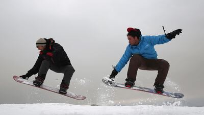 In this Friday, Jan. 24, 2020 photo, Ahmad Sorush, 22, left, and Nizaruddin Alizada, 20, make a jump on the snow-covered hillside known as Kohe Koregh, on the outskirts of Kabul, Afghanistan. AP
