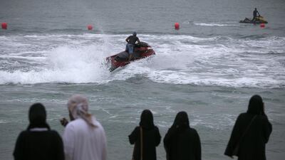 People watch jetskiers while enjoying the cooler weather.