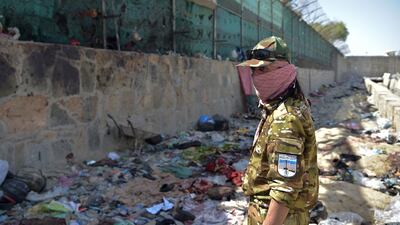 A Taliban fighter stands guard at the site of the explosions, which killed scores of people, at Kabul airport. AFP