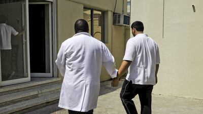 Teacher Honest Ncube (left) holds a teenager by his arm as they return to the classroom at the Dubai Autism Centre. Jaime Puebla / The National