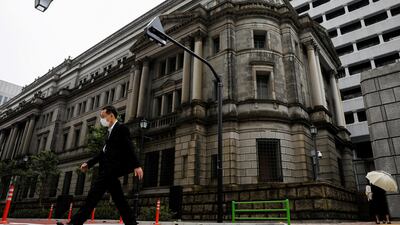 A man wearing a protective mask walks past the headquarters of the Bank of Japan. The Japanese central bank has refused traders' request to work from home despite a rise in Covid-19 cases in Tokyo. Reuters.
