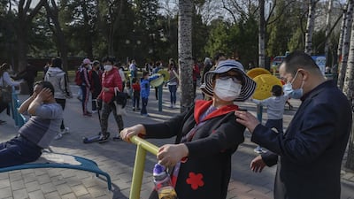 A Chinese woman wears a protective mask as she exercises on equipment at Ritan Park in Beijing, China. Getty Images