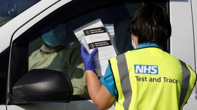An NHS Test and Trace staff member holds Covid-19 kits at a centre in Bolton, England. Photo: Reuters