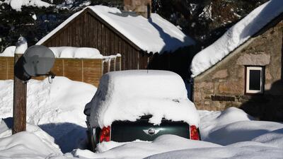 A car sits trapped by snow in a driveway. Getty Images