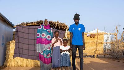 Forty-year-old Hamra Ibrahim Hamed, left, with her three children in front of their shelter in the Farchana refugee camp
