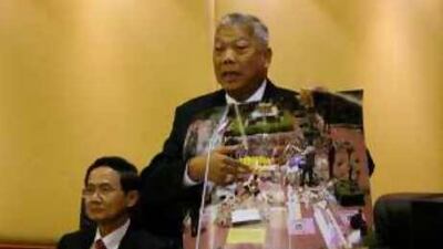 Samak Sundaravej, Thailand's prime minister, holds a photograph of protesters displaying weapons as he speaks in Bangkok yesterday.