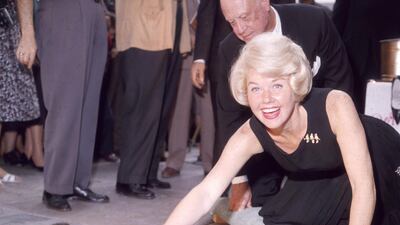 American singer and actress Doris Day smiling as she signs her name in cement by her handprints, in front of Mann's (formerly Grauman's) Chinese Theater, on Hollywood Boulevard, Hollywood, California in January 1961. Hulton Archive / Getty Images