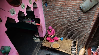 Marjina Bano,18, sits with a basket filled with tobacco flakes and cotton thread, rolling bidis.