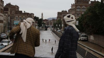 People watch boys playing in floodwater in the old quarter of Sanaa, Yemen. Reuters