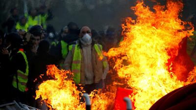 Protesters wearing yellow vests are seen behind a fire as they attend a demonstration of the 'yellow vests' movement in Angers, France. Reuters