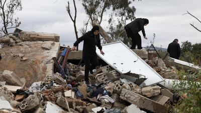 Assaad Bzih, a displaced Lebanese resident, and his family walk on rubble near their destroyed home in Zibqin. Reuters