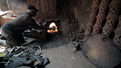 An Egyptian worker puts the wood inside a traditional oven at a pottery workshop in Old Cairo, Egypt.