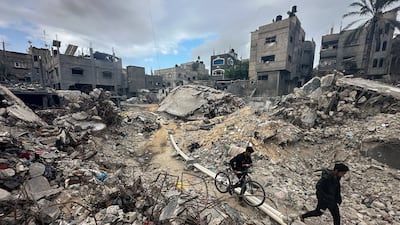 Palestinians walk among the rubble, as they inspect houses destroyed in Israeli strikes. Reuters