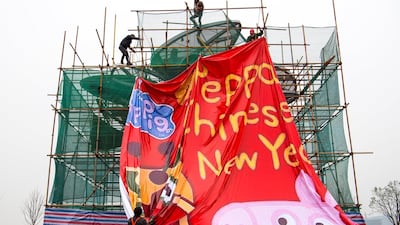 Men work on covering up a sculpture under construction with a tarpaulin with an image of Peppa Pig. Reuters