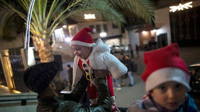 A Palestinian Christian man plays with his baby as they wait for the Christmas Mass outside the Holy Family Catholic Church in Gaza City. AP Photo