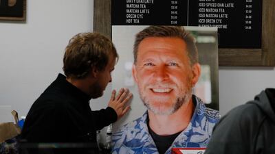 Jordan Hopkins places his hand on the photo of Sean Adler during a vigil at the Rivalry Roasters coffee shop. AP Photo