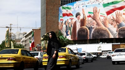 A woman walks past a billboard featuring an image of the late Supreme Leader of Iran, Ayatollah Ali Khamenei, in Tehran. Reuters