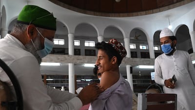 A health worker inoculates a student with a dose of the CanSino Biologics vaccine at Jamia Naeemia seminary in Lahore, Pakistan.