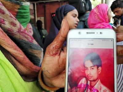 Relatives show pictures of family members who became victims of the deadly violence in Delhi. Taniya Dutta for The National