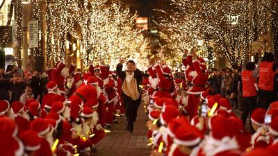 People dressed in Santa Claus costumes attend a parade under winter illuminations at Marunouchi business district in Tokyo. AFP