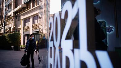 A man walks past a sign saying "2021 Happy New Year" on a shopping street in Shanghai, China. Reuters