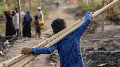 A Rohingya refugee carries bamboo sticks to a temporary shelter after a fire destroyed a Rohingya refugee camp on Saturday night, in New Delhi, India, June 14, 2021. REUTERS/Danish Siddiqui
