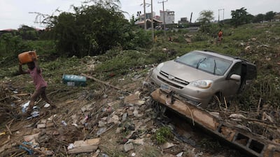 A man walks past a car swept by floodwaters in Abuja, Nigeria, in 2021. AFP