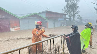 Firefighters rescue a woman from surging flood waters in Canlaon city. AFP